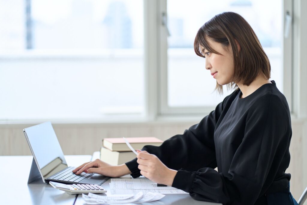 Asian woman entering expenses in accounting software