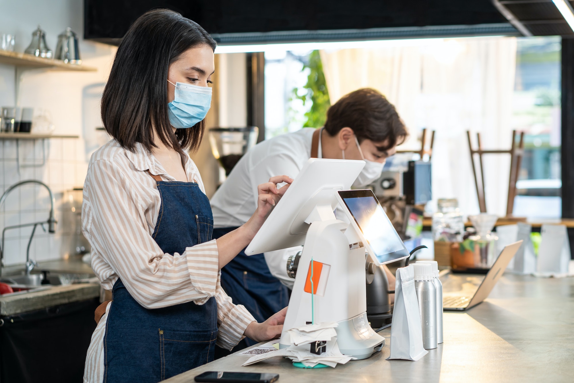 Asian cafe business wear mask, use laptop check food order and payment.