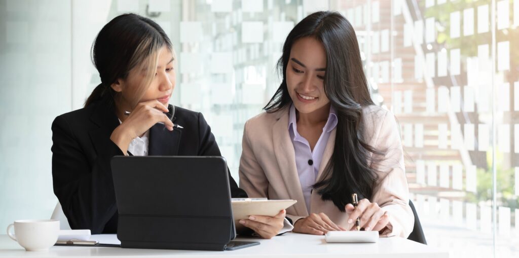 Two beautiful young asian businesswoman working together using digital tablet at office.