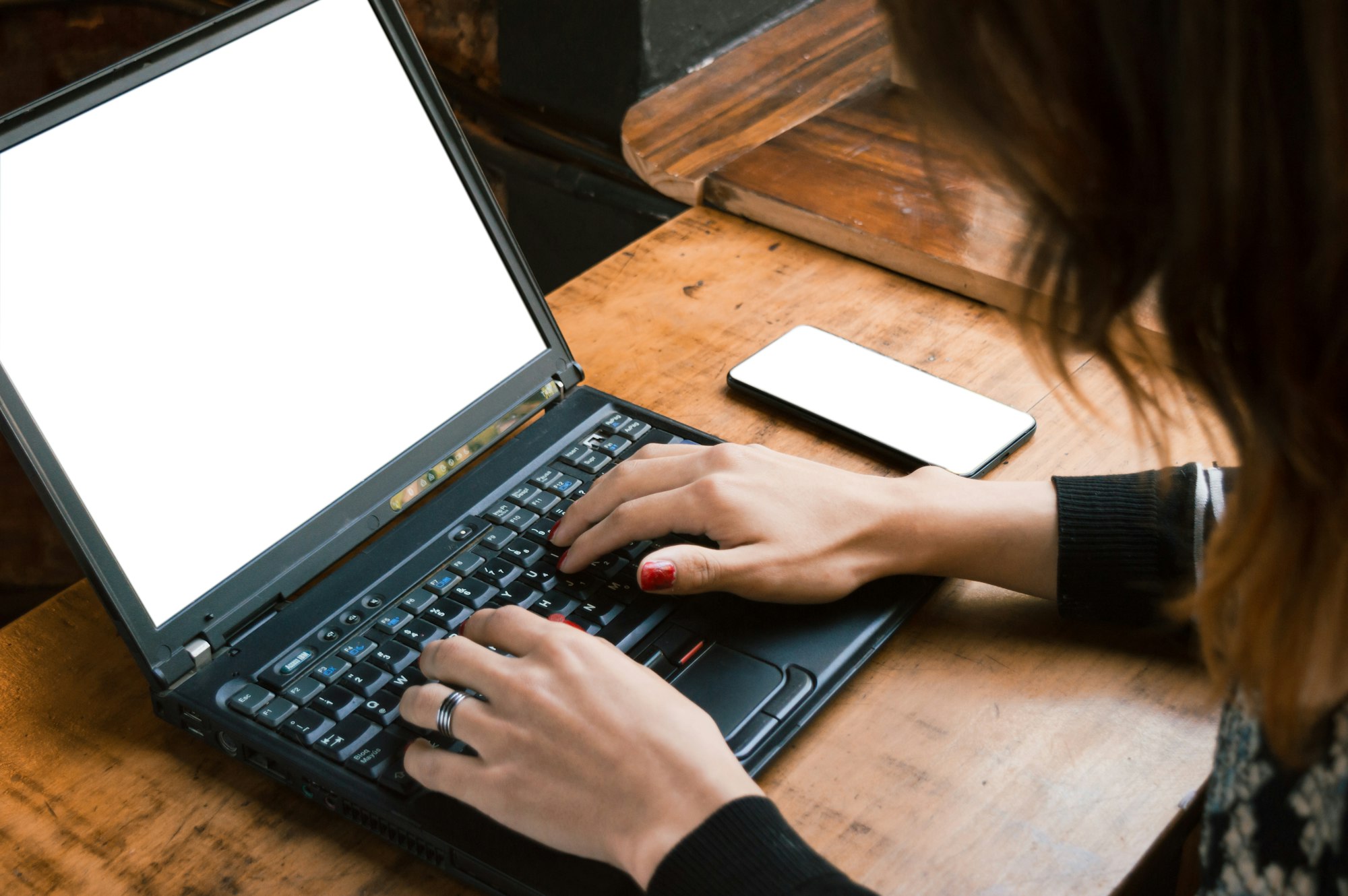 Unrecognizable young business woman typing on her laptop working in a restaurant.